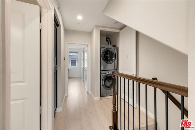 corridor with light hardwood / wood-style flooring and stacked washer and clothes dryer