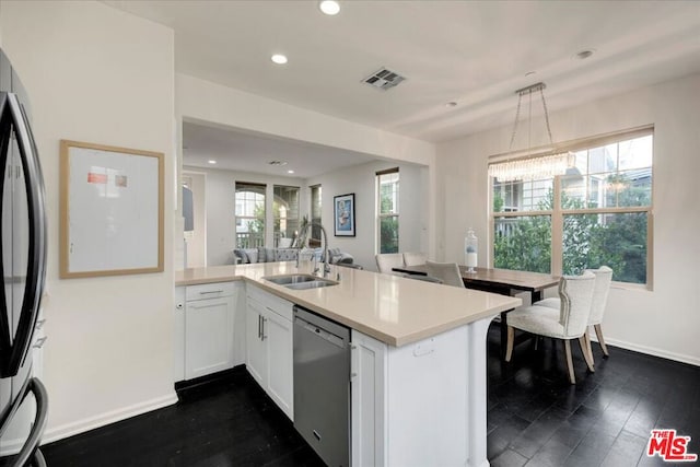 kitchen with pendant lighting, sink, stainless steel dishwasher, white cabinetry, and kitchen peninsula