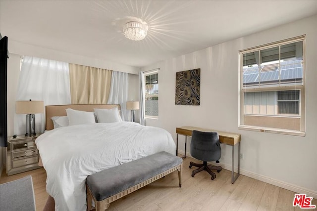 bedroom with an inviting chandelier and light hardwood / wood-style flooring