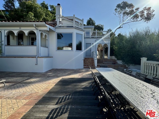 back of property featuring a balcony and a patio area