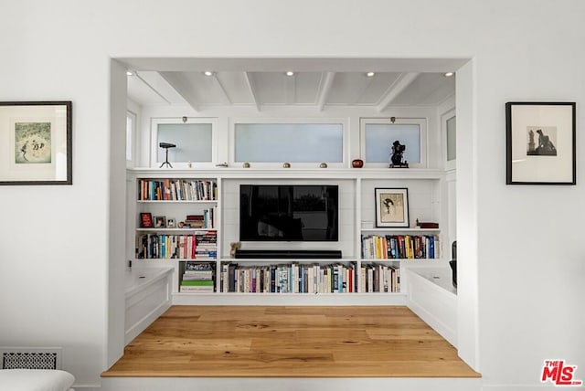 living area with beamed ceiling and wood-type flooring