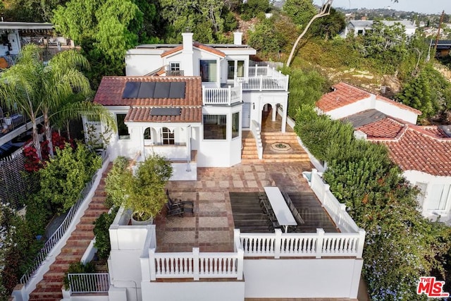 back of property with solar panels, a patio, and a balcony