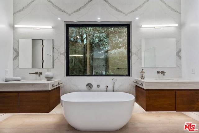 bathroom featuring vanity, a tub to relax in, and expansive windows