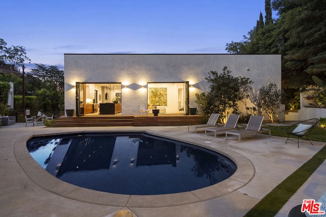 pool at dusk featuring a patio