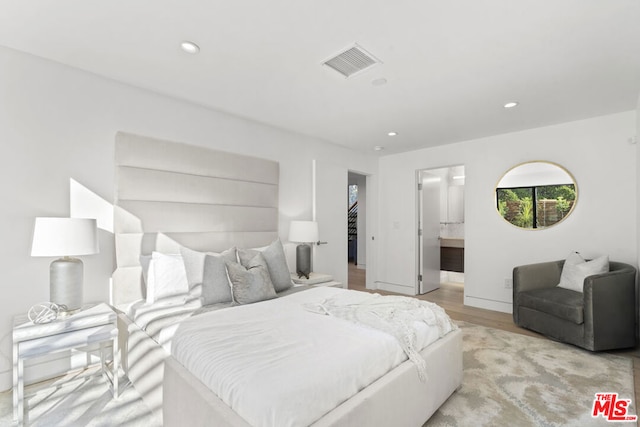 bedroom featuring connected bathroom and light hardwood / wood-style flooring