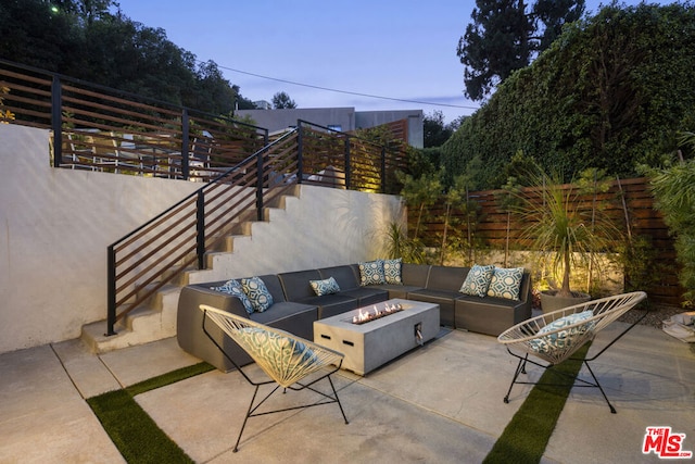 patio terrace at dusk with an outdoor living space with a fire pit