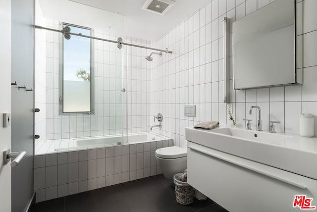 full bathroom featuring tile patterned floors, vanity, tile walls, toilet, and tiled shower / bath