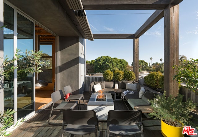 view of patio with a wooden deck and an outdoor living space with a fire pit