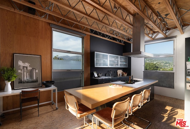 kitchen featuring sink, beam ceiling, hardwood / wood-style flooring, wooden ceiling, and a breakfast bar area