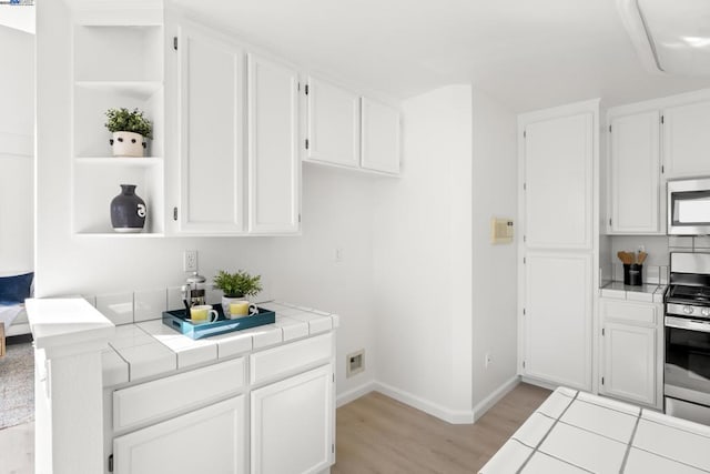 kitchen with tile counters, white cabinetry, and appliances with stainless steel finishes