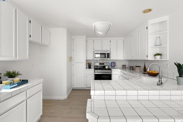 kitchen with sink, stainless steel appliances, tile countertops, and white cabinetry