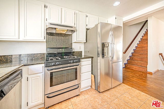 kitchen featuring dark stone countertops, white cabinets, light tile patterned flooring, and appliances with stainless steel finishes