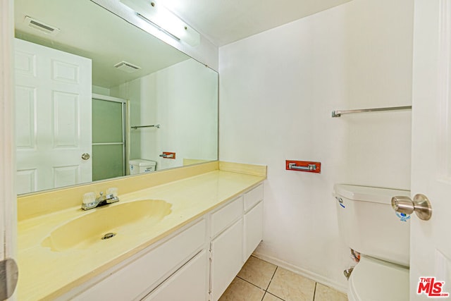 bathroom with tile patterned flooring, vanity, toilet, and walk in shower