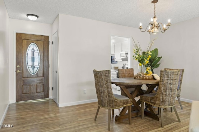 dining area with a textured ceiling, hardwood / wood-style flooring, and a notable chandelier