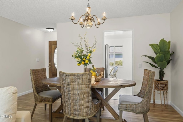 dining room featuring hardwood / wood-style floors, a textured ceiling, and a notable chandelier