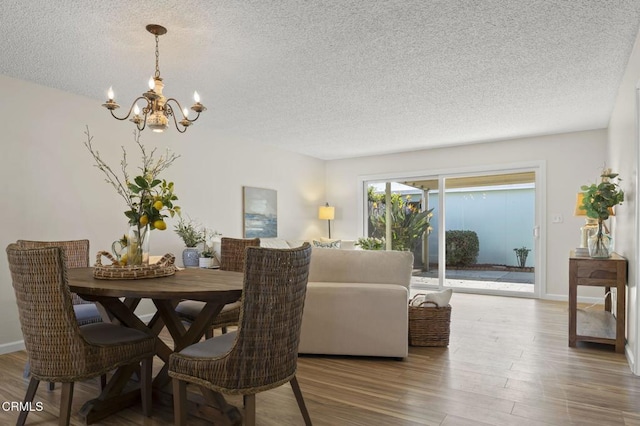 dining room featuring a notable chandelier, wood-type flooring, and a textured ceiling