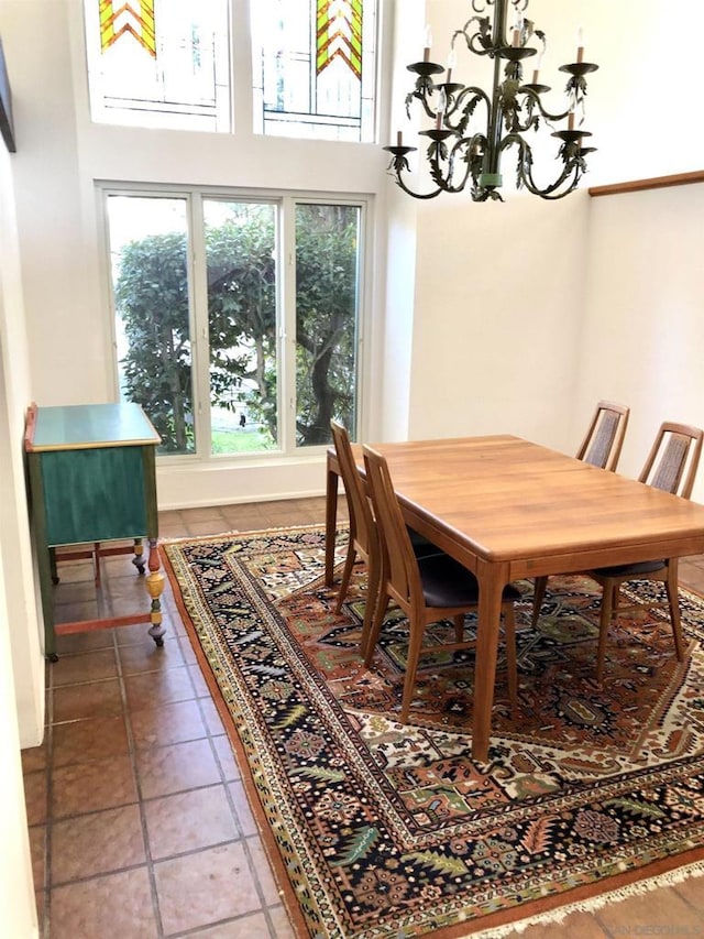 dining room with a notable chandelier, tile patterned flooring, and a towering ceiling