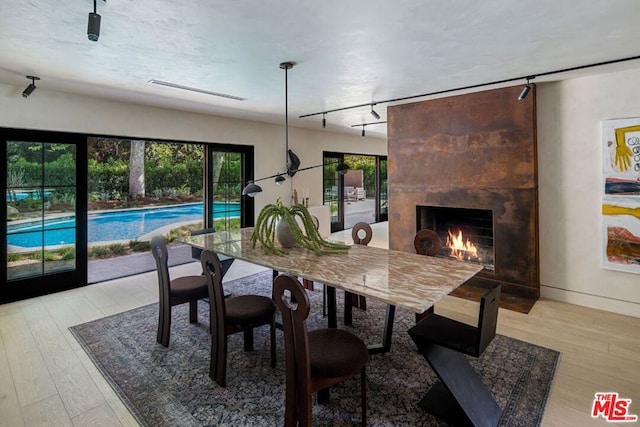 dining area featuring light hardwood / wood-style floors, a fireplace, and track lighting