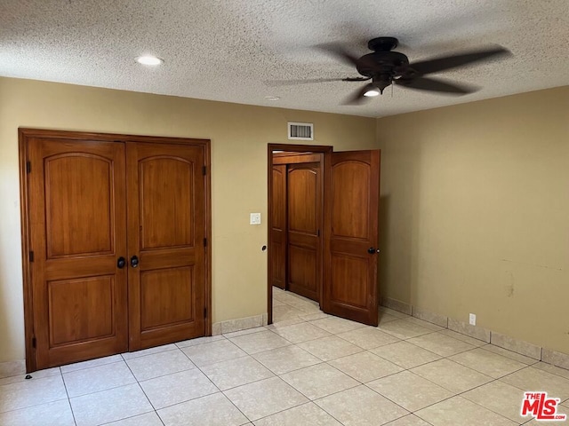 unfurnished bedroom with light tile patterned floors, a textured ceiling, and ceiling fan