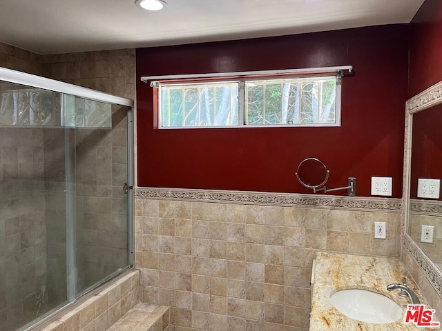 bathroom with vanity, tile walls, and walk in shower