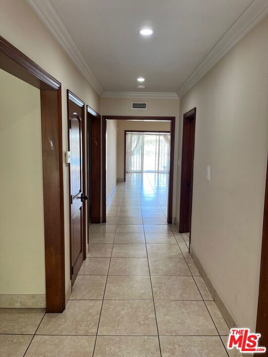 corridor with crown molding and light tile patterned flooring