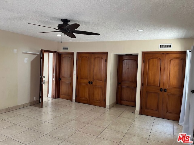 unfurnished bedroom with a textured ceiling, ceiling fan, and light tile patterned flooring