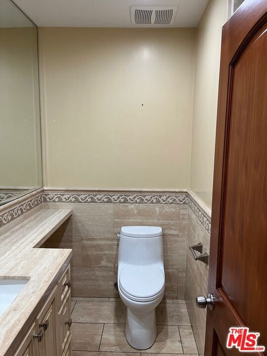 bathroom with tile patterned floors, vanity, tile walls, and toilet