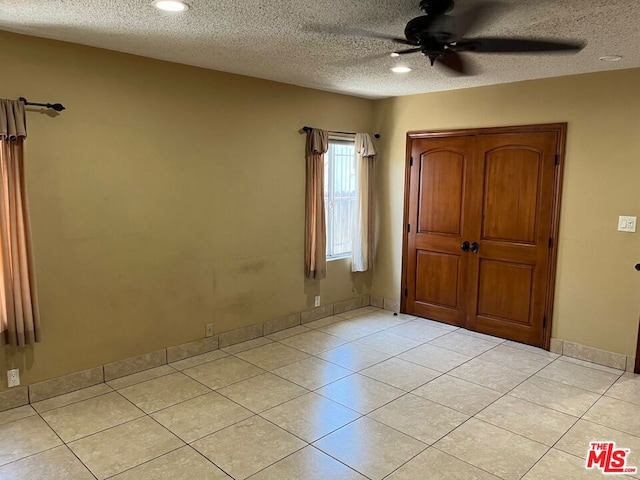 unfurnished bedroom featuring a textured ceiling, ceiling fan, and light tile patterned flooring