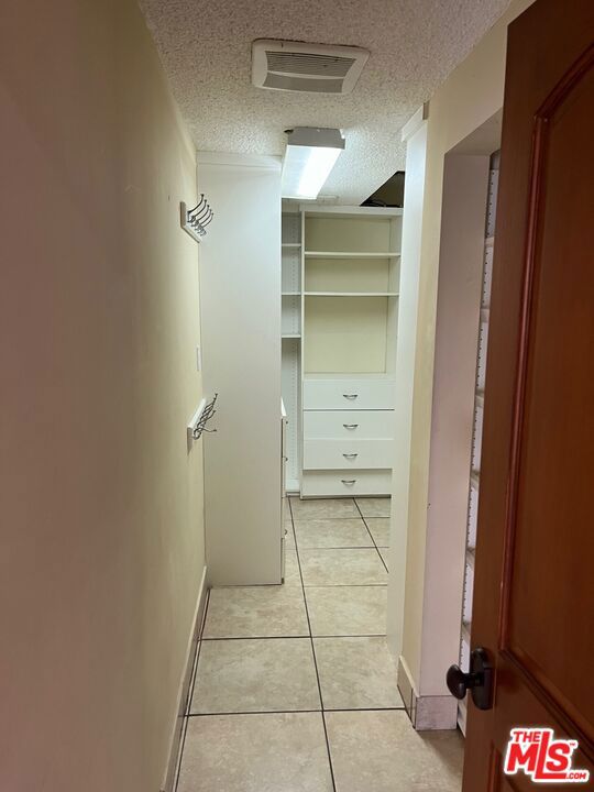 hall featuring light tile patterned flooring and a textured ceiling