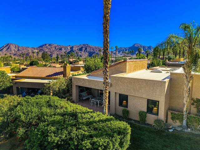 exterior space with a mountain view, exterior fireplace, and a patio area