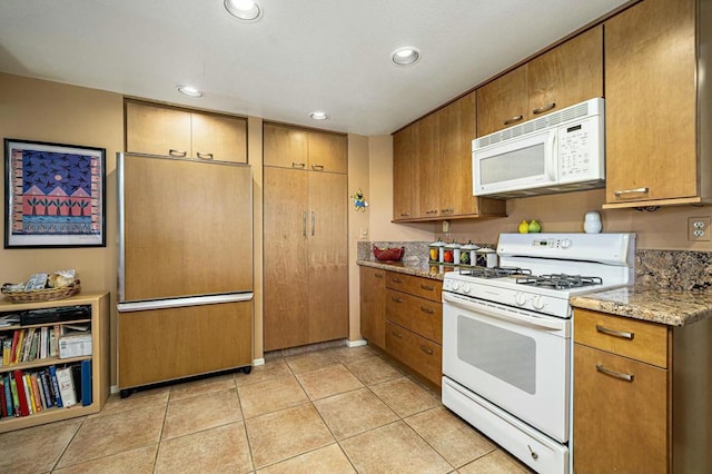 kitchen with light stone counters, light tile patterned floors, and white appliances