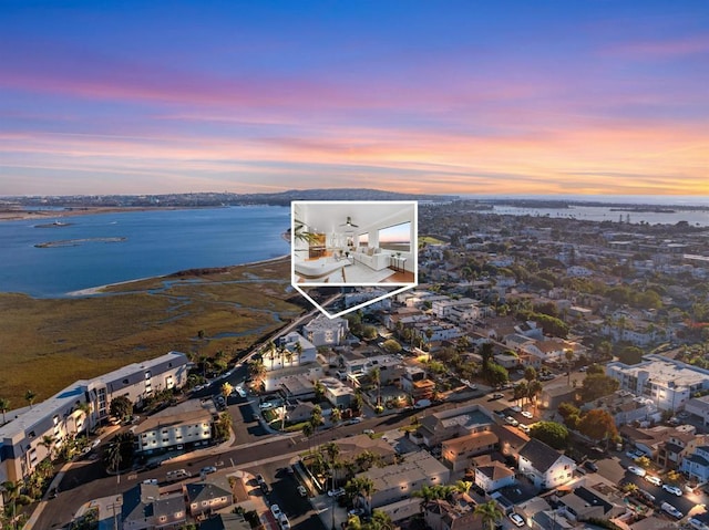 aerial view at dusk featuring a water view