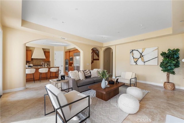 living room featuring a raised ceiling and sink