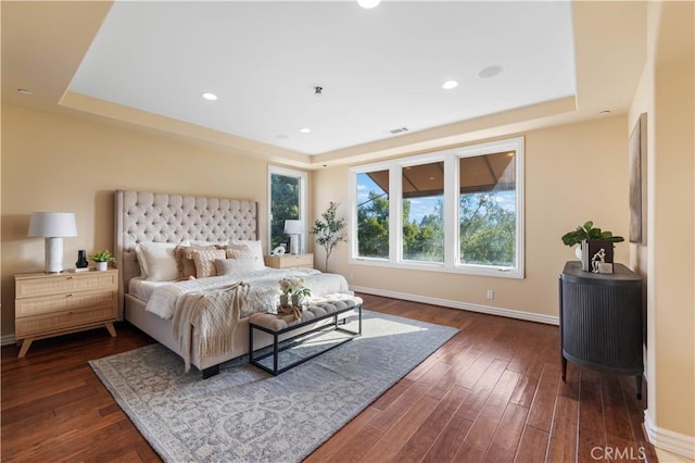 bedroom with dark wood-type flooring and a tray ceiling