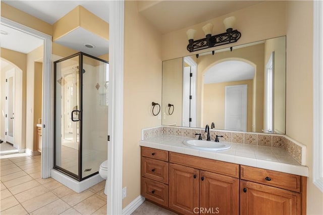 bathroom featuring tile patterned flooring, vanity, a shower with door, and toilet