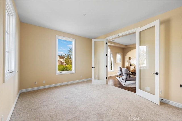 carpeted spare room with a wealth of natural light and french doors