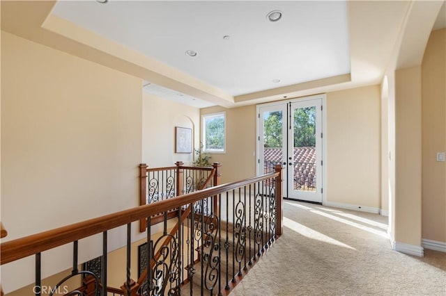 corridor featuring carpet and a tray ceiling