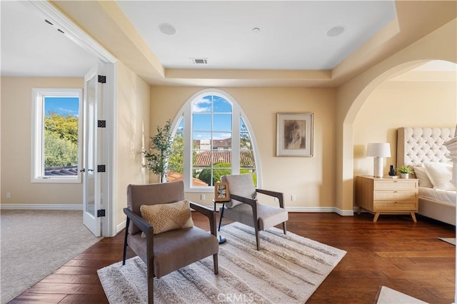 sitting room with a tray ceiling, a wealth of natural light, and dark hardwood / wood-style flooring