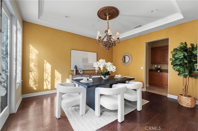 dining space featuring a chandelier, dark hardwood / wood-style flooring, a raised ceiling, and plenty of natural light