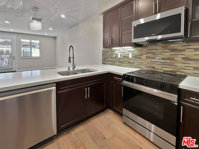 kitchen featuring stainless steel appliances, sink, light wood-type flooring, tasteful backsplash, and dark brown cabinets