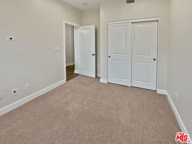 unfurnished bedroom featuring a closet and light carpet