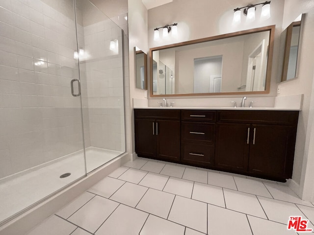 bathroom with a shower with door, vanity, and tile patterned floors