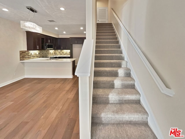 stairway featuring wood-type flooring and sink