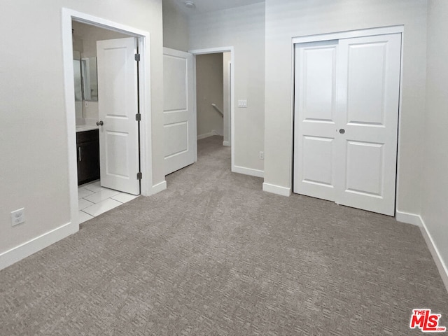 unfurnished bedroom featuring ensuite bathroom and light colored carpet