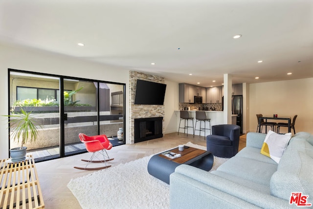 living room featuring a stone fireplace and light parquet flooring