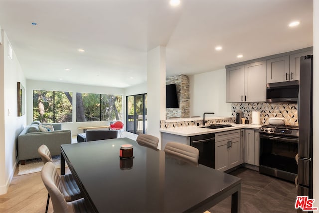 kitchen featuring sink, stainless steel appliances, backsplash, kitchen peninsula, and gray cabinets