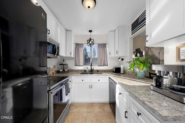 kitchen with white cabinetry, sink, black refrigerator, and hanging light fixtures