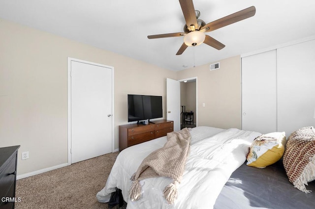 carpeted bedroom with a closet, visible vents, baseboards, and ceiling fan