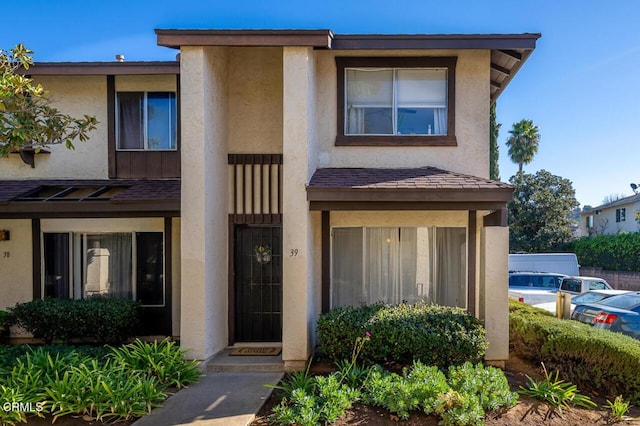 multi unit property featuring a shingled roof and stucco siding