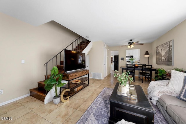 living room with visible vents, a ceiling fan, stairway, light tile patterned flooring, and baseboards